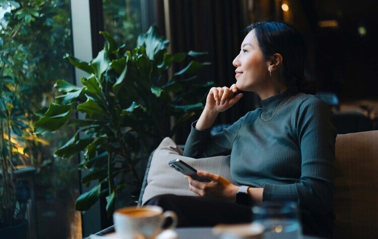Femme assise sur un canapé regardant par la fenêtre