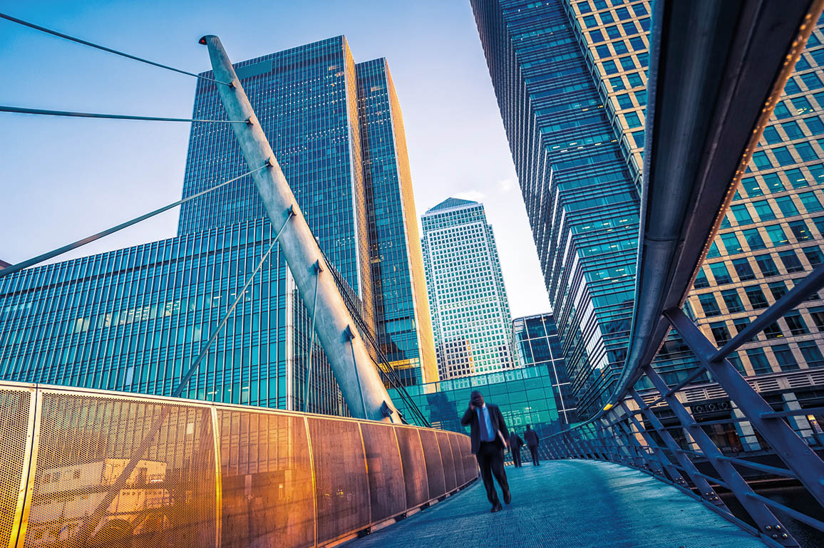Intelligent Workforce Management Innenstadt mit Glasbürogebäuden; Ein Mann läuft über eine Fussgängerbrücke