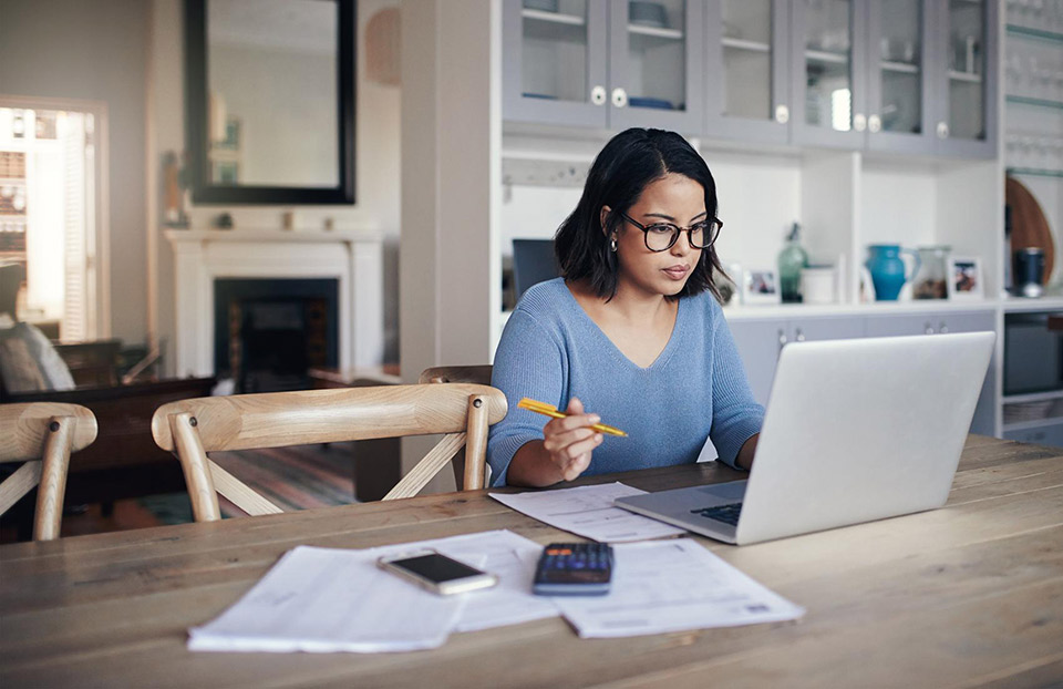 Junge Frau arbeitet aus dem Home Office an ihrem Laptop