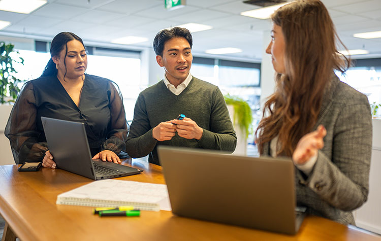 Eine Gruppe von drei Mitarbeitern tauscht sich aus