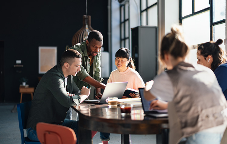 Eine Gruppe von Mitarbeitenden besprechen etwas an einem gemeinsamen Tisch
