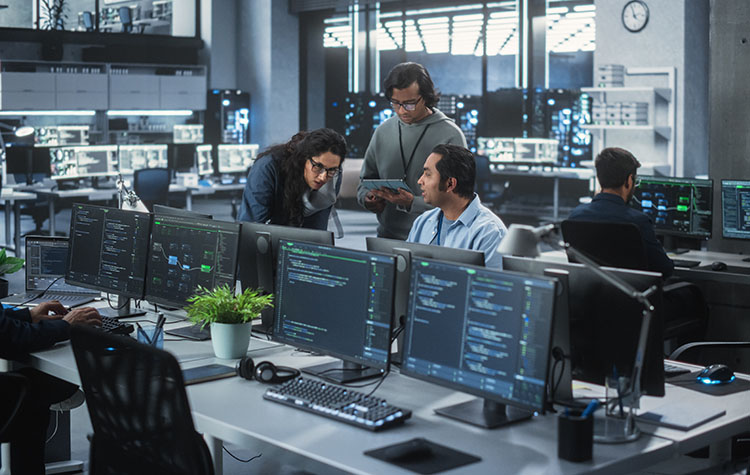 A group of three software engineers discussing a topic in an IT office.