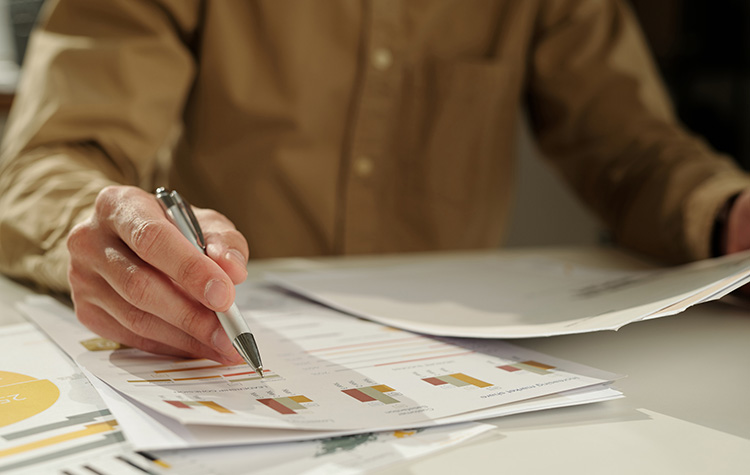 A person holding a pen and many documents