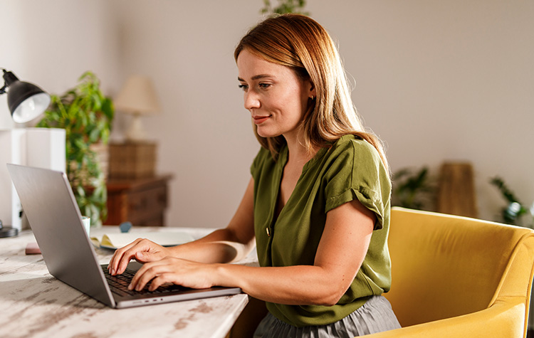Eine blonde Dame schreibt an ihrem Laptop