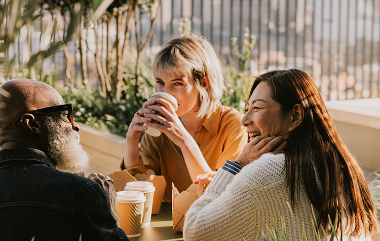 Drei Freunde trinken Kaffee in einem Garten.